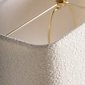 Lámpara de sobremesa de estilo art deco fabricado en travertino en color marrón combinado con hierro en color oro y algodón bouclé en color blanco roto. Producto desmontable.