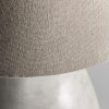 Lámpara de sobremesa de estilo contemporáneo fabricado en cemento en color blanco con acabado decapado combinado con algodón en color marrón. Producto desmontable elevable.
