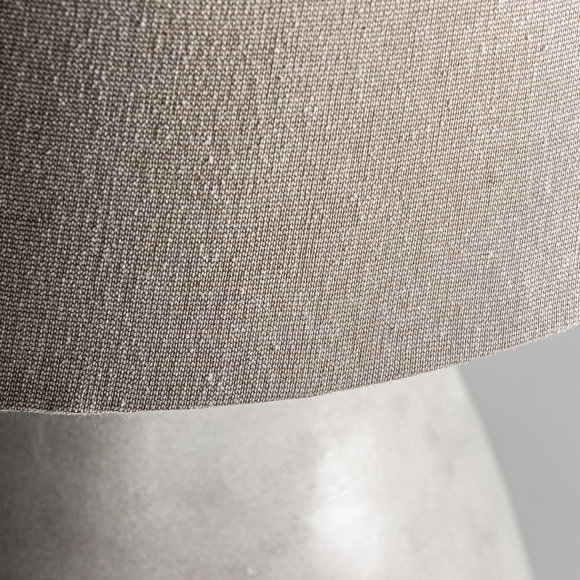 Lámpara de sobremesa de estilo contemporáneo fabricado en cemento en color blanco con acabado decapado combinado con algodón en color marrón. Producto desmontable elevable.