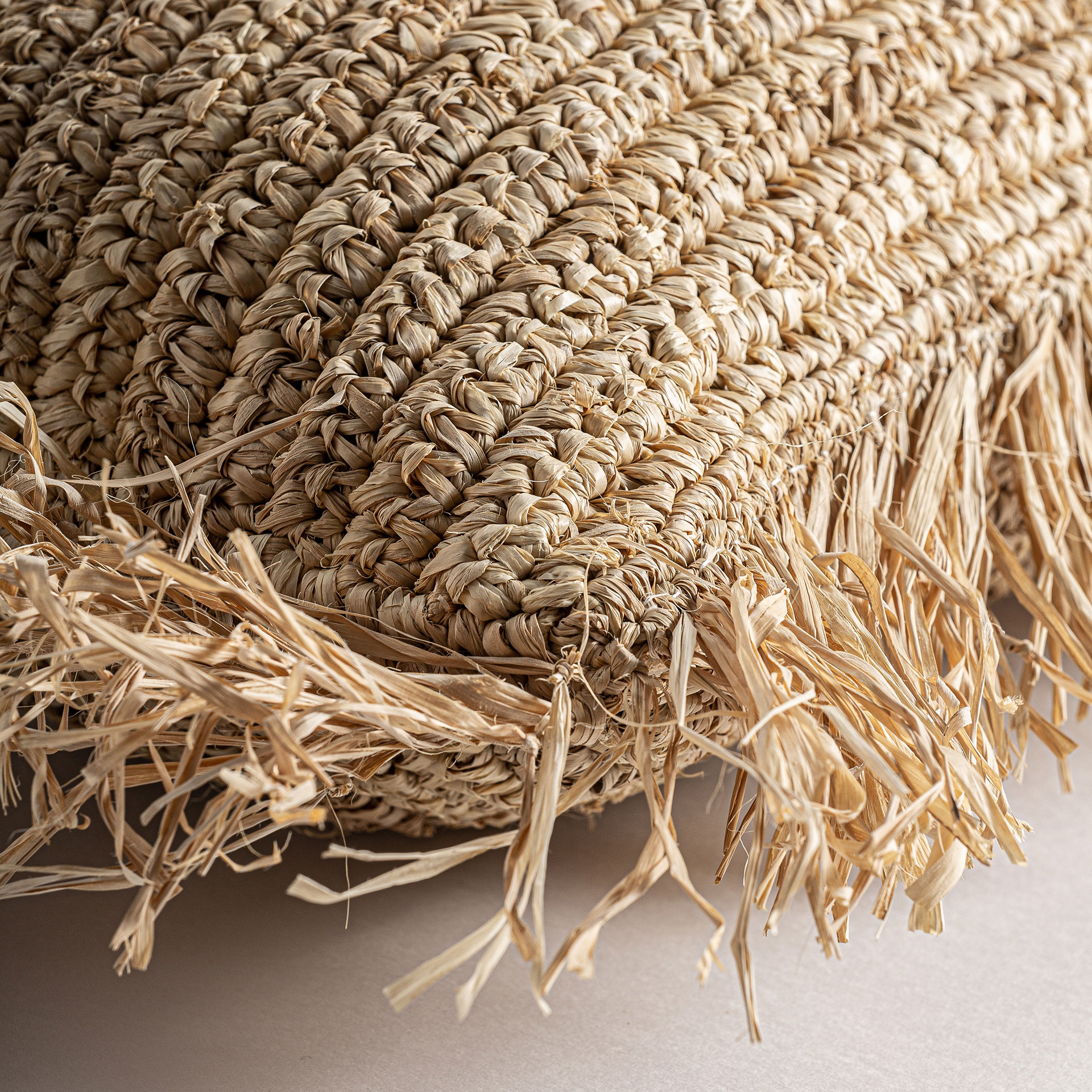 Cojín igotz de estilo boho fabricado en fibra natural en color beige combinado con poliéster.