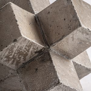 Figura decorativa Kubo de estilo contemporáneo fabricado en cemento en color beige con acabado tallado combinado con arena.