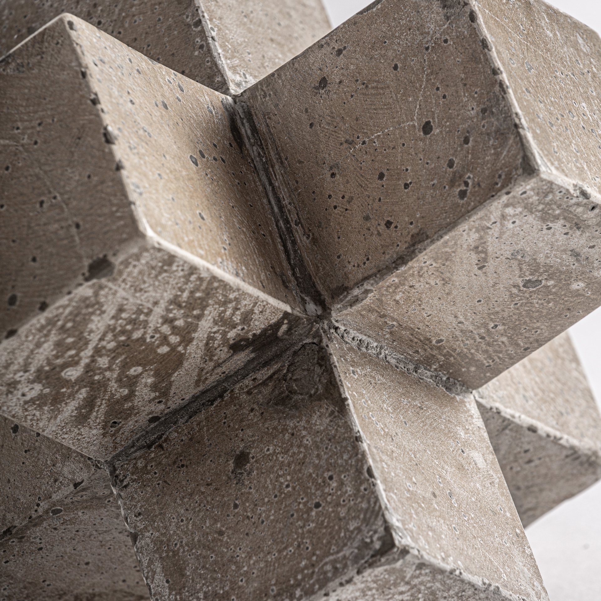 Figura decorativa Kubo de estilo contemporáneo fabricado en cemento en color beige con acabado tallado combinado con arena.