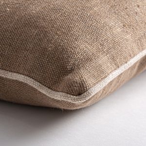 Cojín Nahia de estilo clásico fabricado en lino en color marrón combinado con fibra natural. Producto desenfundable.